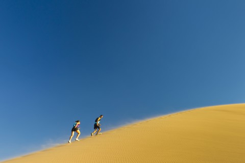 Hispanic couple climbing sand dune