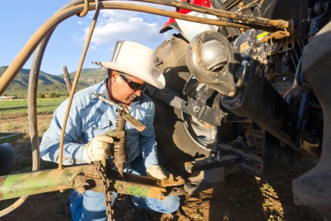 Hispanic farmer working on tractor