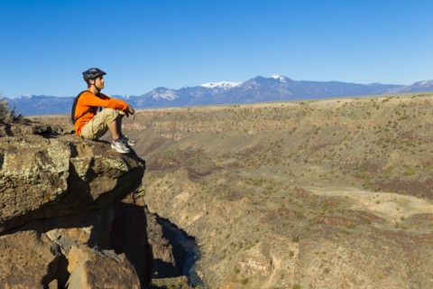Hispanic man sitting on canyon cliff