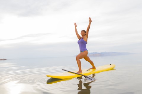 Filipino woman practicing yoga on paddle board