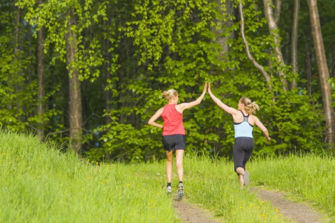 Caucasian runners high fiving on path