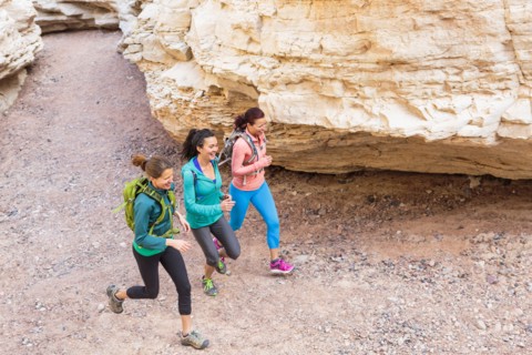 Women running in canyon wearing backpacks