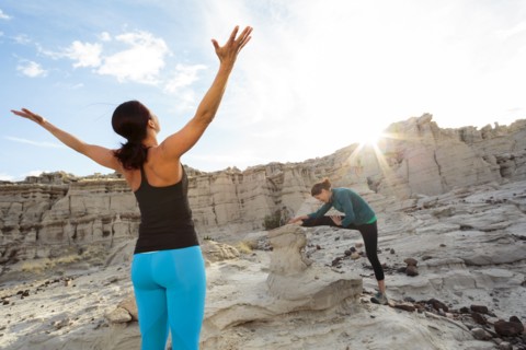 Women stretching arms and legs in canyon