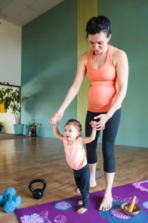 Mixed Race expectant mother holding hands of daughter on exercise mat