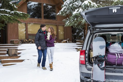 Caucasian couple walking to car with snowboards in winter