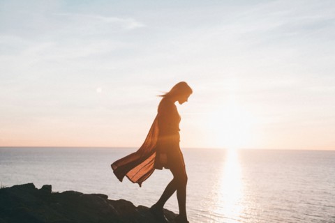 Silhouette of Caucasian woman walking on rocks at ocean