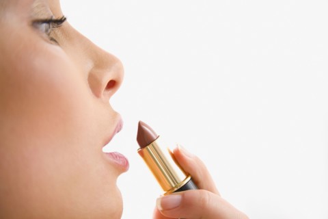 Mixed race woman applying lipstick