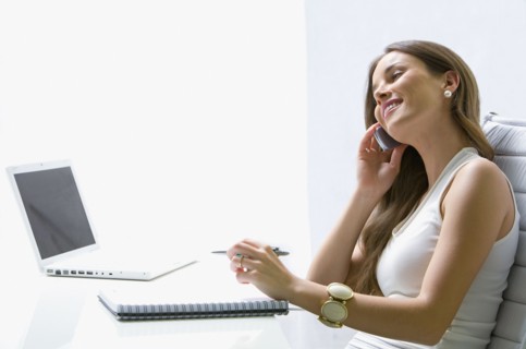 Mixed race businesswoman talking on cell phone at desk