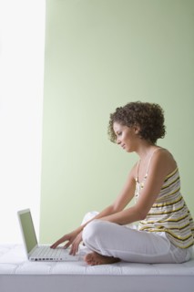 Mixed race woman sitting on sofa using laptop