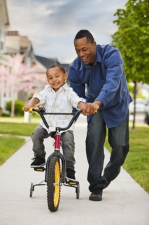 Father teaching son to ride bicycle