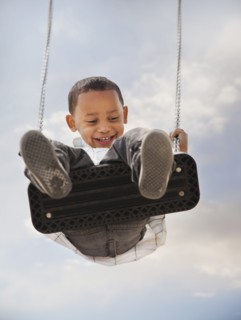 Mixed race boy swinging