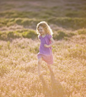 Caucasian girl running through field of flowers