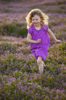 Caucasian girl running through field of flowers