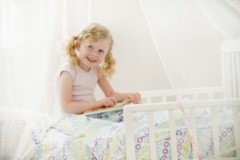 Caucasian girl reading in bed