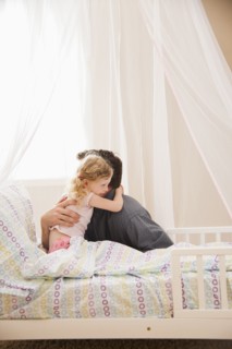 Caucasian father hugging daughter in bed