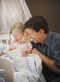 Caucasian father reading book to daughter in bed