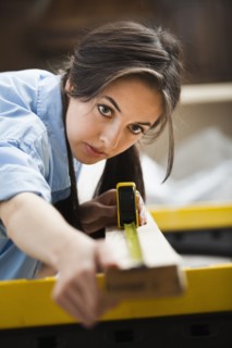 Caucasian woman measuring wood