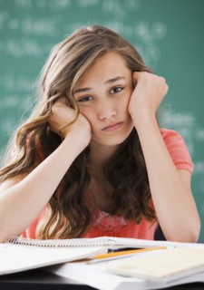 Bored Caucasian teenager studying on classroom