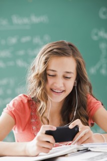 Caucasian teenager listening to mp3 player in classroom