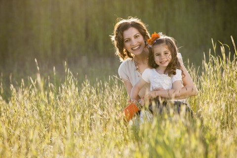 Caucasian mother and daughter sitting in grass