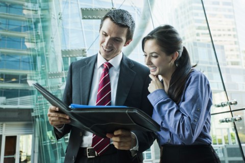 Caucasian business people looking at notebook together