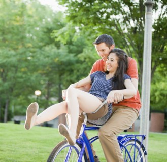 Caucasian couple riding bicycle together
