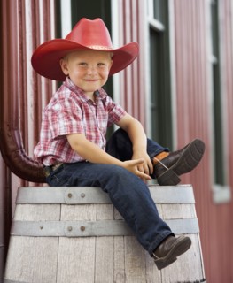 Caucasian cowboy sitting on barrel