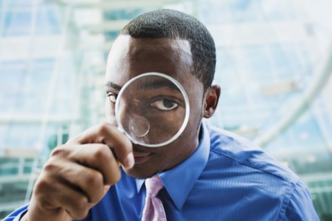 Black businessman using magnifying glass
