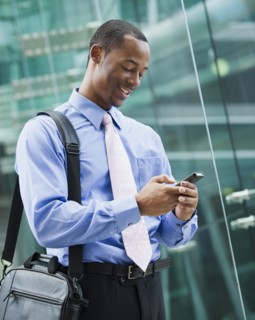 Black businessman text messaging on cell phone