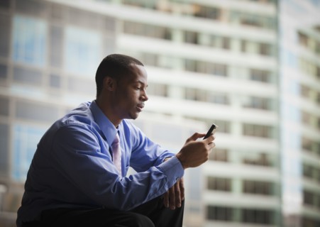 Black businessman text messaging on cell phone