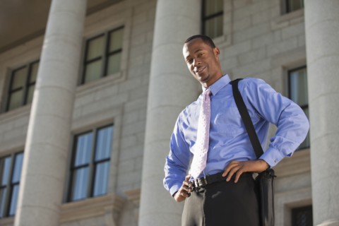 Black businessman standing outdoors with hands on hips