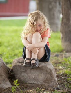 Smiling Caucasian girl sitting on rock
