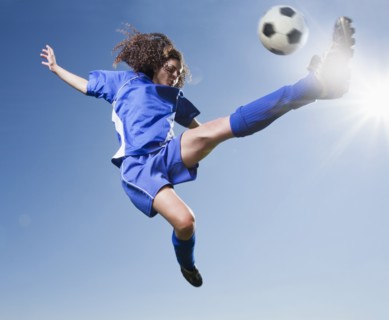 Caucasian woman kicking soccer ball