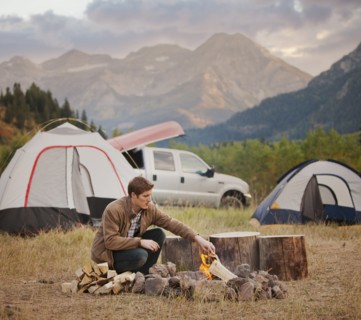 Caucasian man building campfire at campsite