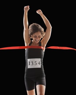 Caucasian woman running across race finish line