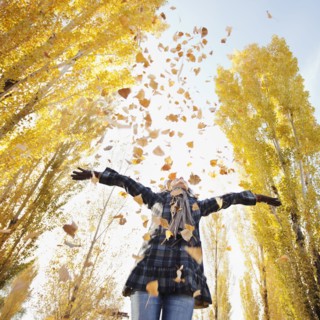 Caucasian woman playing with autumn leaves
