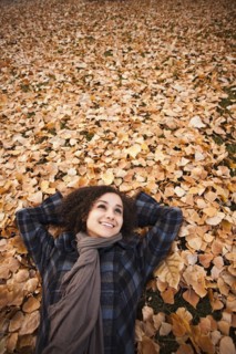 Caucasian woman laying in autumn leaves