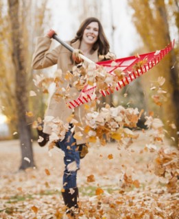 Caucasian woman raking autumn leaves