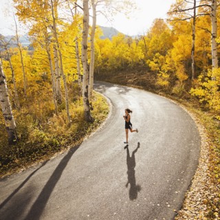 Caucasian woman running along autumn road