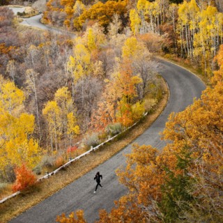 Caucasian woman running along autumn road