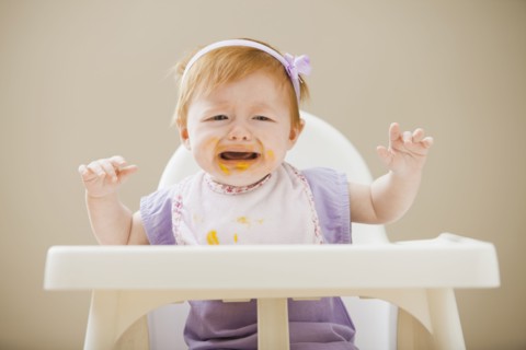Caucasian baby girl crying in high chair