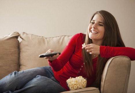 Caucasian woman watching television and eating popcorn