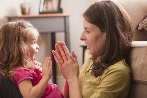 Caucasian mother and daughter playing clapping game