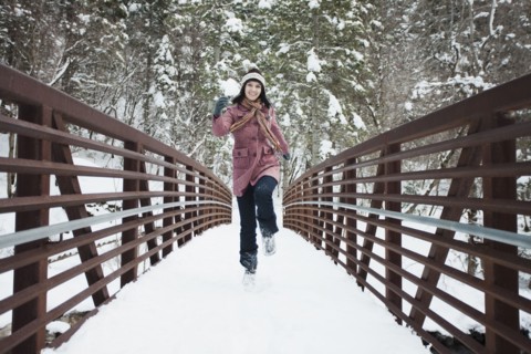 Caucasian woman crossing snow covered bridge