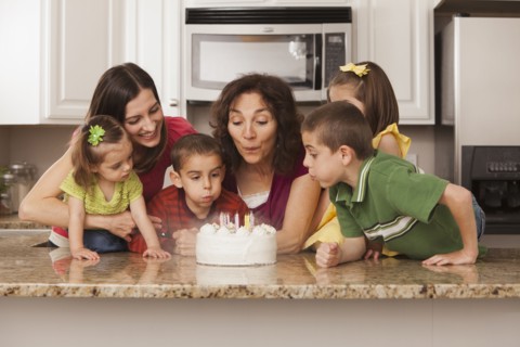 Caucasian family in kitchen blowing out birthday cake