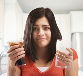 Caucasian woman holding glasses of soda and water