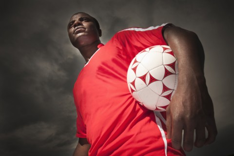 Black soccer player holding ball
