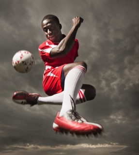 Black soccer player kicking ball