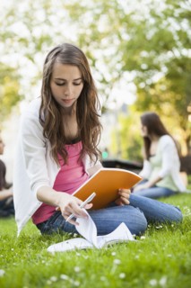 Caucasian woman studying in grass