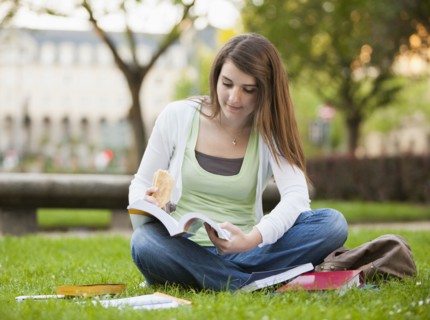 Caucasian student sitting in grass studying